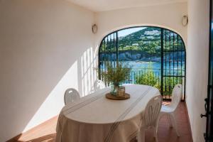 a white table with white chairs and a large window at Maridea - Donatino a Mare in Ponza