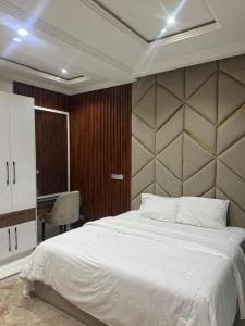 a bedroom with a large white bed and a desk at Verse Living in Abuja