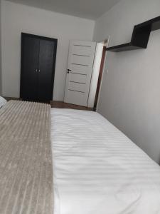 a bedroom with a bed with white sheets and a door at Apartmán VERDE in Suchá Hora