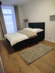 a bedroom with a bed with a black headboard and a rug at Apartmán VERDE in Suchá Hora