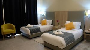 a hotel room with two beds and a yellow chair at EVASION by LIBERTE in Oran