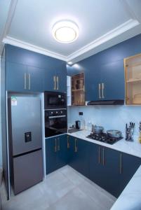 a kitchen with blue cabinets and a stainless steel refrigerator at Elazoh Apartments in Kisumu