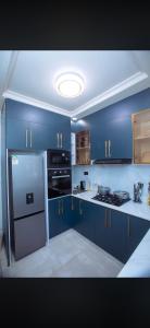 a kitchen with blue cabinets and a stainless steel refrigerator at Elazoh Apartments in Kisumu