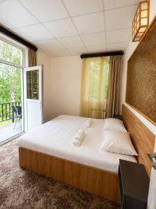a bedroom with a large bed and a large window at Sochi Resort-Pine Garden Boutique Hotel and Pool Stepanavan in Stepʼanavan