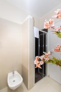 a bathroom with a sink and a toilet and flowers at Resid Enza Palazzo Sciacca in Patti