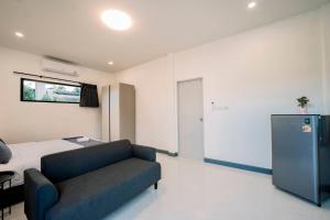 a bedroom with a couch and a bed and a refrigerator at NS Khaolak Resort in Khao Lak +1 photo