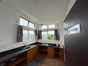 a kitchen with a sink and a counter with windows at Kesang Stay in Diphu