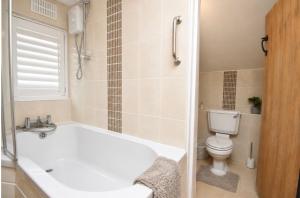 a bathroom with a white tub and a toilet at Lennon cottage in Hale +12 photos