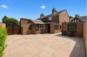 a patio in front of a brick house at Lennon cottage in Hale