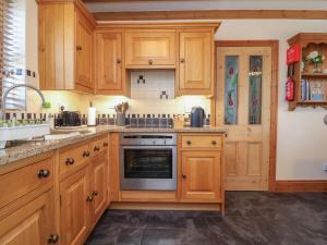 a kitchen with wooden cabinets and a sink and a stove at Ash Farm Cottage in Holywell