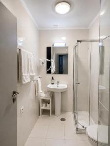 a white bathroom with a sink and a shower at Guest House Vimaranes in Guimarães +40 photos