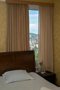 a bedroom with a bed and a large window at Kutaisi Grand Suites in Kutaisi