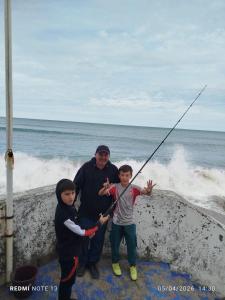 a man and two children standing next to the ocean at Arena & mar in Las Grutas