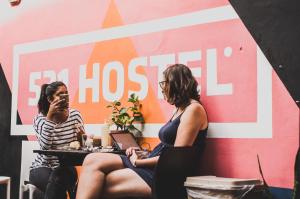 two women sitting at a table in front of a wall at 531 Hostel in Cordoba