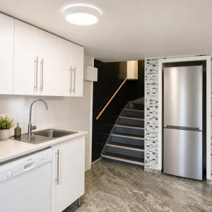a kitchen with a stainless steel refrigerator and a staircase at Bokloster Longstay in Märsta