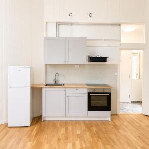 a kitchen with white cabinets and a sink and a refrigerator at Bokloster Longstay in Märsta