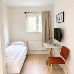 a small white room with a bed and a desk at Bokloster Longstay in Märsta