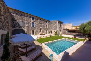 a house with a swimming pool and an umbrella and chairs at Domaine Croix-Maro in Caux
