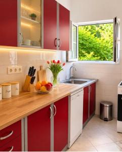 a kitchen with red cabinets and a bowl of fruit on a counter at Sun House in Kumbor
