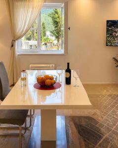 a table with a bowl of fruit and a bottle of wine at Sun House in Kumbor