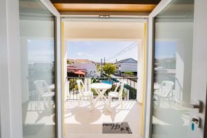 a glass door leading to a balcony with a table and chairs at Pátio Mariano in Serra de El-Rei