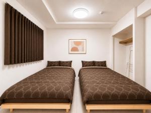 two beds in a room with white walls at Excel 琴似 -FIX HOME- in Sapporo