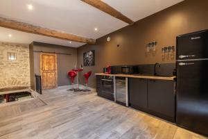 a large kitchen with black appliances and wooden floors at l'Envoûtée, suite de charme in Sérignan-du-Comtat