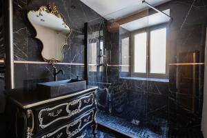 a black bathroom with a sink and a mirror at l'Envoûtée, suite de charme in Sérignan-du-Comtat