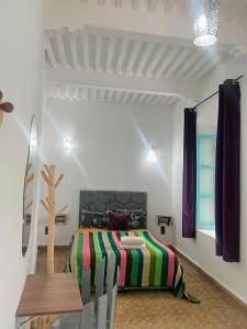 a bedroom with a bed and a wooden table at Riad Darko in Essaouira