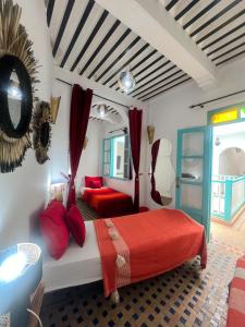 a bedroom with a bed with red pillows and a mirror at Riad Darko in Essaouira