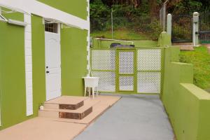 a green and white house with a white door and stairs at Middleham Forest Nook in Roseau