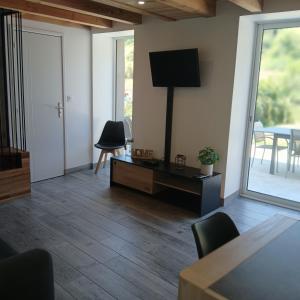 a living room with a television and a table and chairs at Le Nolan in Cublize