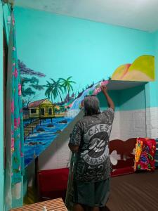 a person painting a mural of a beach at Pousada Conexão in Itaúnas