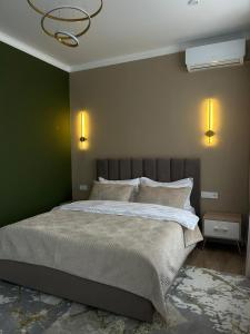 a bedroom with a large bed with a green wall at Verde Hotel in Semey