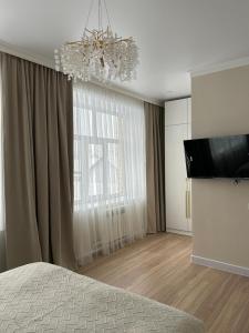 a bedroom with a chandelier and a large window at Verde Hotel in Semey