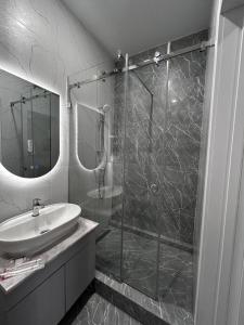 a bathroom with a glass shower and a sink at Verde Hotel in Semey