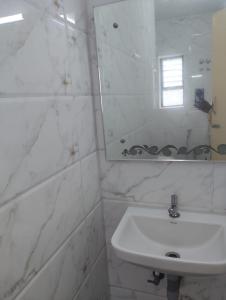 a white bathroom with a sink and a mirror at Hotel ESS Paradise in Coimbatore +25 photos