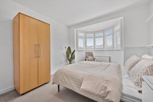 a bedroom with a bed and a wooden cabinet at 2 Bed Flat 10mins Heathrow 1 Parking EV in Hanworth