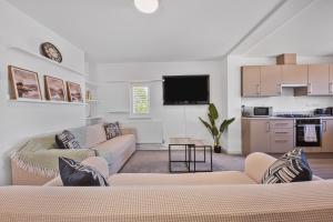 a living room with a couch and a kitchen at 2 Bed Flat 10mins Heathrow 1 Parking EV in Hanworth