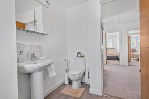 a white bathroom with a sink and a toilet at 2 Bed Flat 10mins Heathrow 1 Parking EV in Hanworth +5 photos