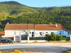 a white house with red roofs in front of a mountain at Alojamientos El Pardal in Molinicos