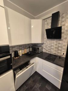a kitchen with white cabinets and black counter tops at Mieszkanie Fordońska 433A blisko Onkologii in Bydgoszcz