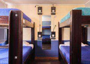 a room with three bunk beds and a mirror at Guanako Rooftop Hostel in Santiago +100 photos