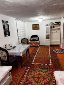 a living room with a table and a kitchen at Nazik Guest House in Barskoon