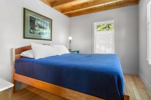 a bedroom with a blue bed and a window at The Boathouse in Brighams Cove