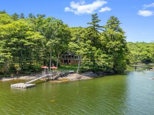 a house on the shore of a lake with a dock at The Boathouse in Brighams Cove