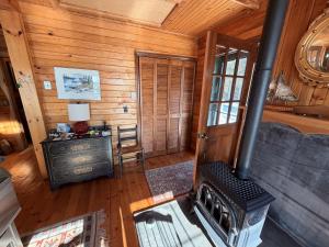 a living room with a stove in a log cabin at Capstone Cottage - Quintessential Cabin on Bay in Gouldsboro