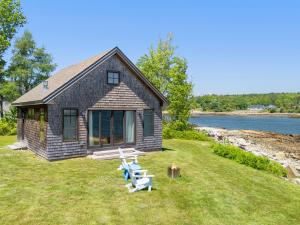 a house with a picnic table and chairs in the grass at Aril Cottage-Waterfront Escape with Ocean Views in Gouldsboro