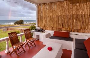 a balcony with a couch and a table with a laptop at Seascape Beach House in Minnie Water