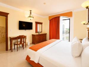 a bedroom with a bed and a desk and a television at Gran Real Yucatan in Mérida